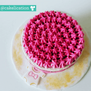Cake making course -looking down on a pink iced cake with student instagram username